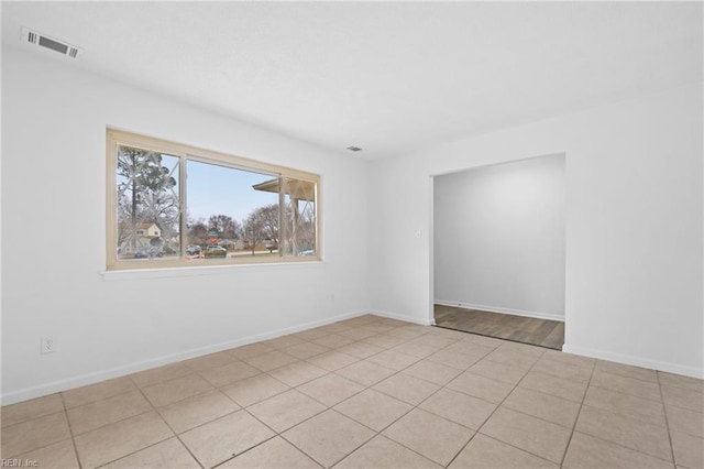 spare room with light tile patterned flooring, visible vents, and baseboards