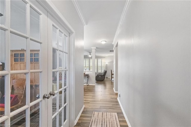 hall with baseboards, ornamental molding, wood finished floors, and french doors