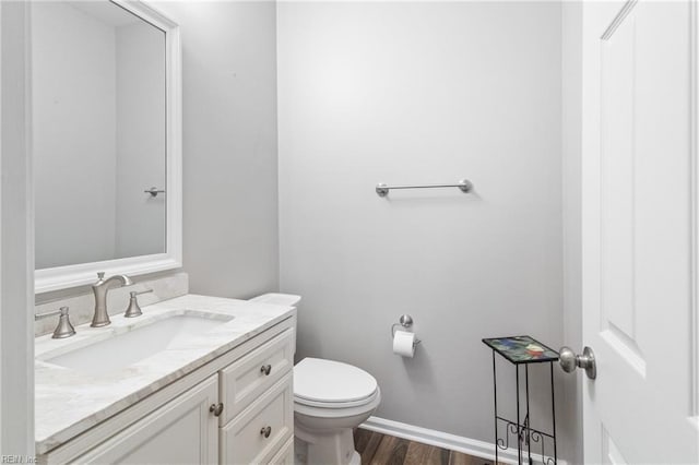 bathroom featuring vanity, wood finished floors, toilet, and baseboards