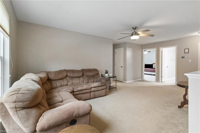 living room featuring light carpet, baseboards, and a ceiling fan