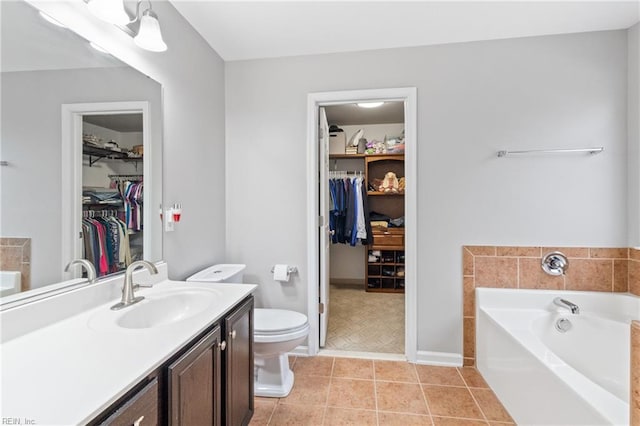 full bath featuring a walk in closet, toilet, vanity, a bath, and tile patterned floors