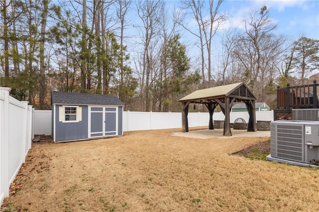 view of yard with central AC unit, a fenced backyard, an outdoor structure, a gazebo, and a storage unit