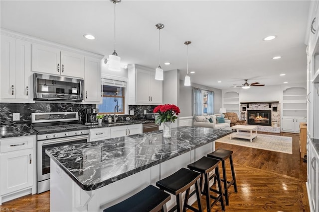 kitchen featuring a center island, appliances with stainless steel finishes, white cabinetry, and a breakfast bar