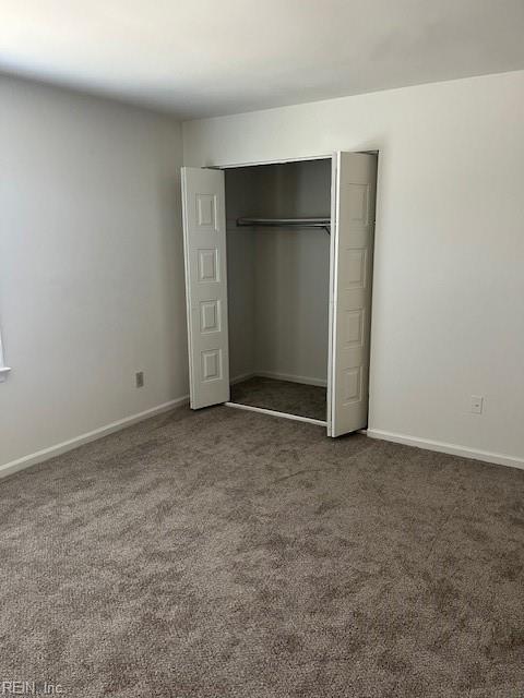 unfurnished bedroom featuring a closet and dark carpet