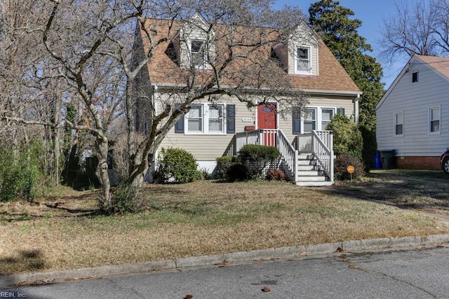 cape cod house with a shingled roof and a front yard