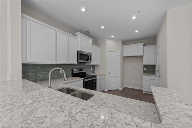 kitchen with white cabinets, appliances with stainless steel finishes, sink, and light stone countertops