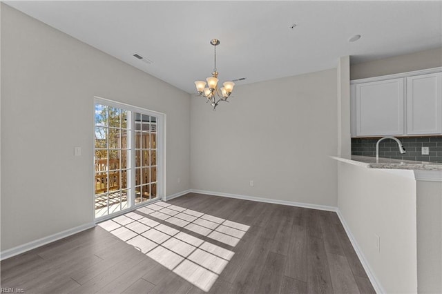 unfurnished dining area featuring dark wood-type flooring and a chandelier