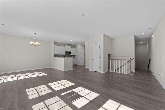 unfurnished living room with dark wood-type flooring and an inviting chandelier