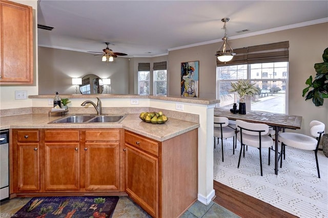 kitchen with a peninsula, a sink, light countertops, ornamental molding, and brown cabinets