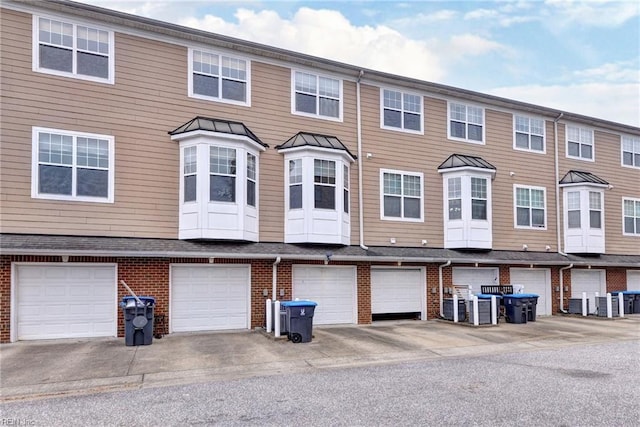 townhome / multi-family property with a garage and brick siding