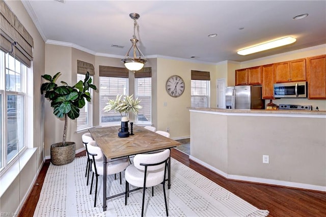 dining space featuring visible vents, crown molding, light wood-style flooring, and baseboards