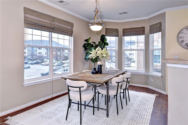 dining room featuring baseboards, plenty of natural light, wood finished floors, and crown molding