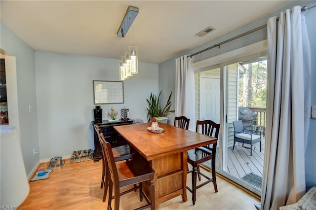 dining room featuring a chandelier, baseboards, visible vents, and light wood finished floors