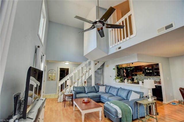 living room with a ceiling fan, stairs, visible vents, and wood finished floors