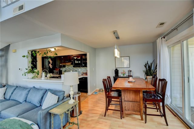 dining area featuring light wood-type flooring and visible vents