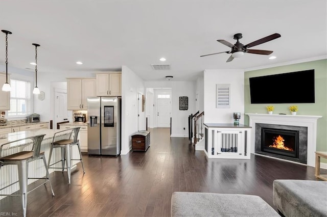 living area with a warm lit fireplace, dark wood-style flooring, visible vents, and recessed lighting