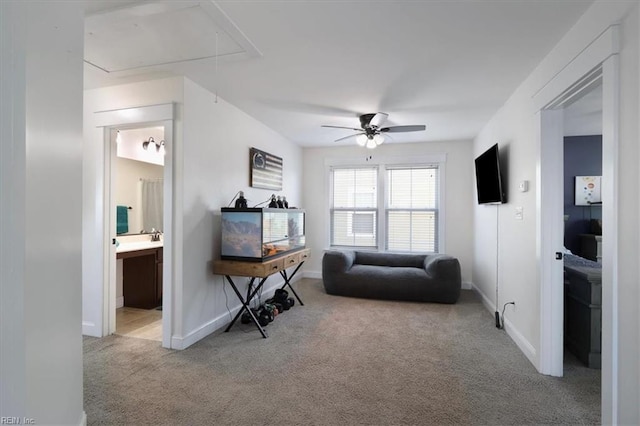 interior space featuring attic access, baseboards, a ceiling fan, and light colored carpet