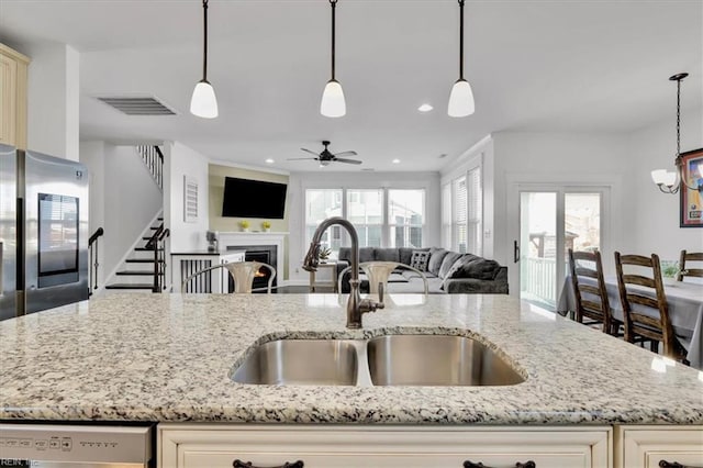 kitchen with hanging light fixtures, refrigerator with glass door, open floor plan, and a sink