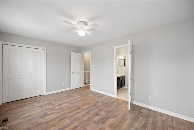 unfurnished bedroom with ceiling fan, a closet, connected bathroom, and hardwood / wood-style floors