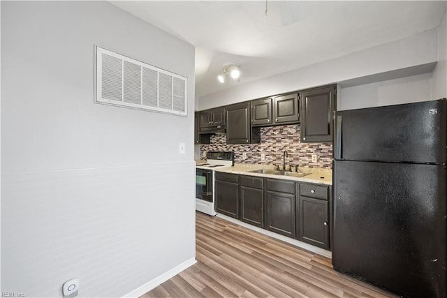 kitchen featuring tasteful backsplash, black refrigerator, light wood-type flooring, white range with electric cooktop, and sink