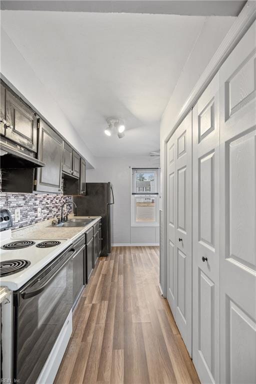 kitchen featuring sink, backsplash, hardwood / wood-style flooring, and white range with electric cooktop