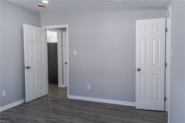 unfurnished bedroom featuring baseboards and dark wood-type flooring