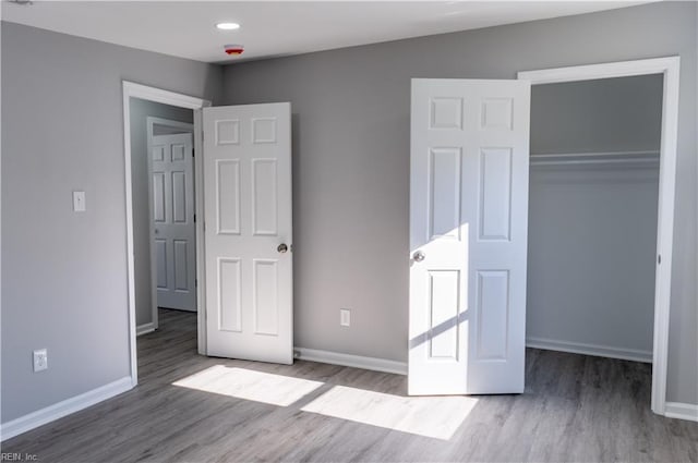 unfurnished bedroom featuring a closet, baseboards, and wood finished floors