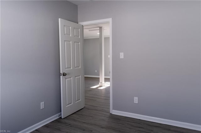 spare room featuring dark wood-style flooring and baseboards