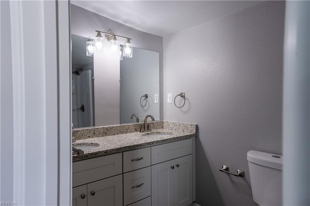 bathroom featuring double vanity, toilet, and a sink