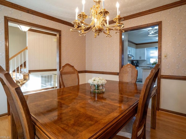 dining area featuring crown molding, visible vents, light wood-style flooring, baseboards, and wallpapered walls