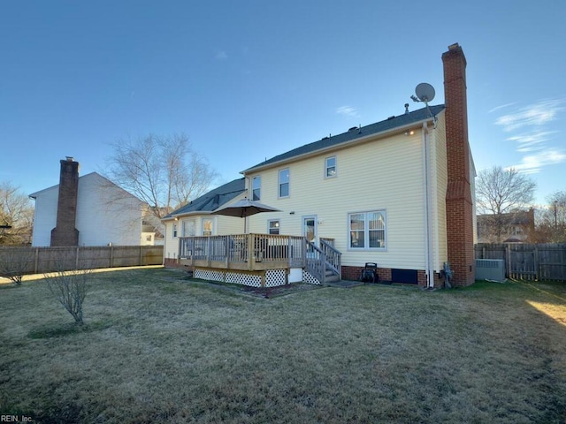 rear view of property featuring a fenced backyard, a chimney, a deck, and a yard