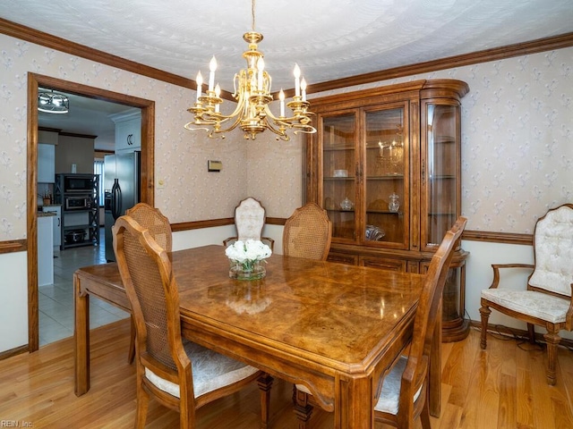 dining room with a chandelier, crown molding, light wood-style flooring, and wallpapered walls