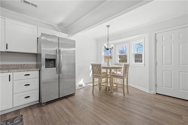 kitchen with light hardwood / wood-style flooring, hanging light fixtures, white cabinets, ornamental molding, and stainless steel fridge with ice dispenser