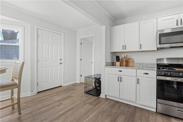 kitchen featuring white cabinetry, light wood-type flooring, light stone countertops, and stainless steel appliances