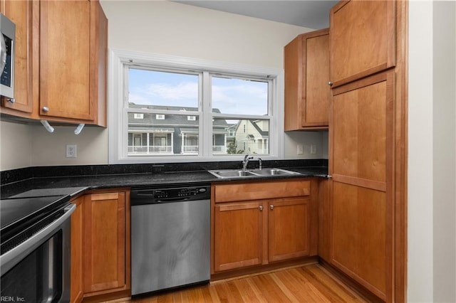 kitchen featuring sink, dark stone countertops, light wood-type flooring, and stainless steel appliances