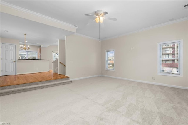 unfurnished living room featuring ceiling fan with notable chandelier, light colored carpet, and ornamental molding