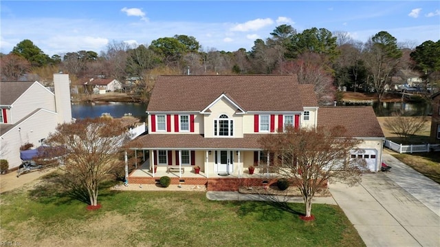 colonial home with a garage, a water view, a front yard, and a porch