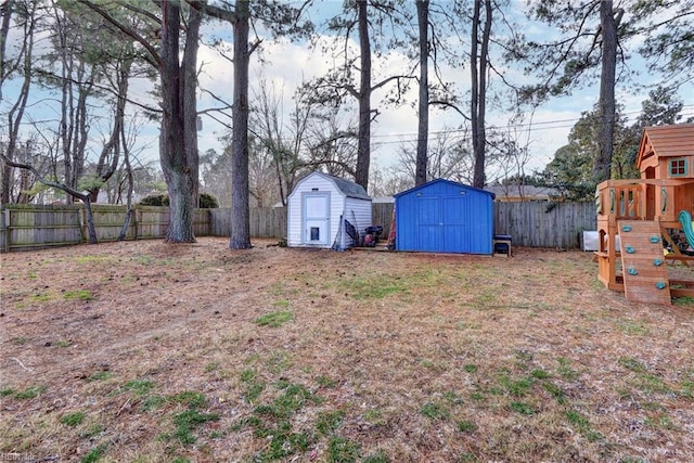 view of yard featuring a storage shed, a fenced backyard, a playground, and an outdoor structure