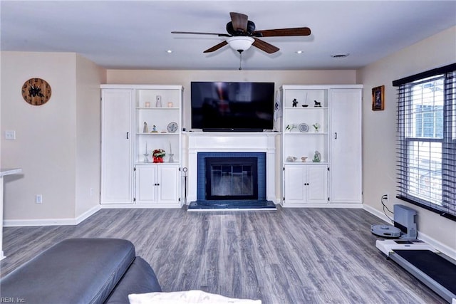 living room featuring baseboards, a fireplace, light wood finished floors, and ceiling fan