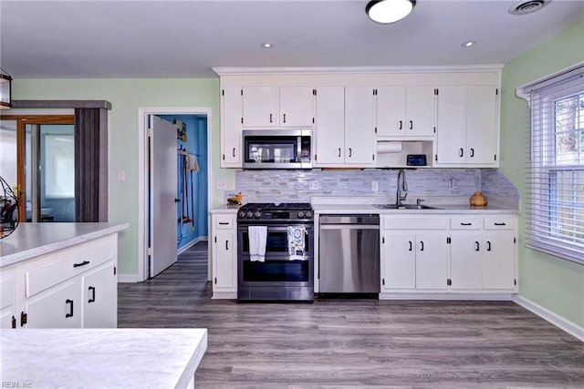 kitchen featuring light countertops, backsplash, appliances with stainless steel finishes, white cabinets, and a sink