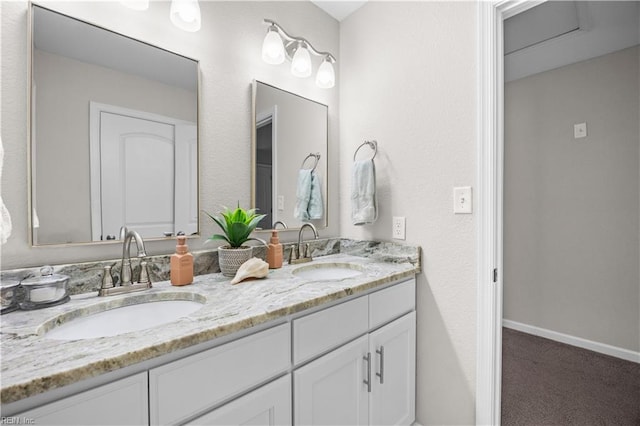 bathroom with a sink, baseboards, and double vanity