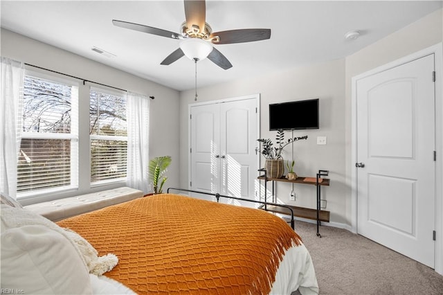 bedroom featuring light carpet, baseboards, visible vents, a ceiling fan, and a closet