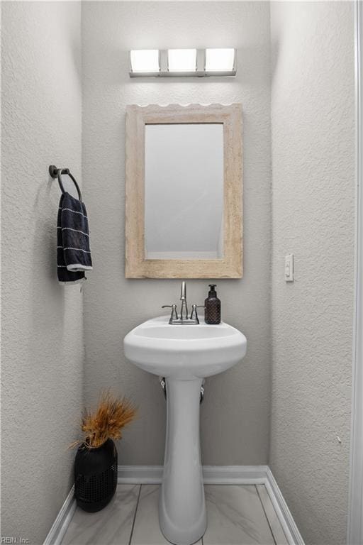 bathroom featuring marble finish floor and baseboards