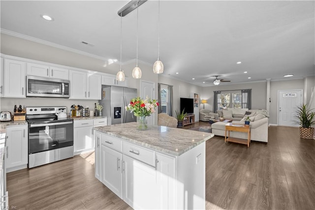 kitchen with a kitchen island, white cabinets, open floor plan, hanging light fixtures, and appliances with stainless steel finishes