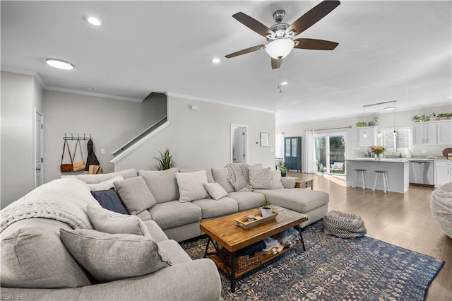 living room with light wood finished floors, ornamental molding, and recessed lighting