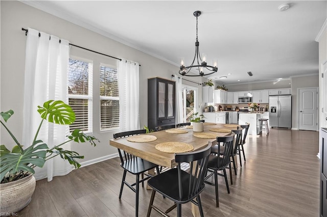 dining area featuring a chandelier, ornamental molding, dark wood finished floors, and baseboards