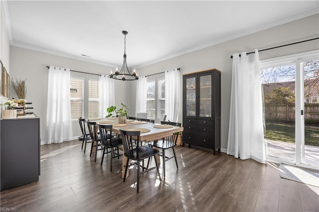 dining room with crown molding, dark wood finished floors, baseboards, and an inviting chandelier