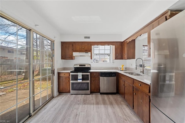 kitchen with visible vents, under cabinet range hood, appliances with stainless steel finishes, light countertops, and a sink