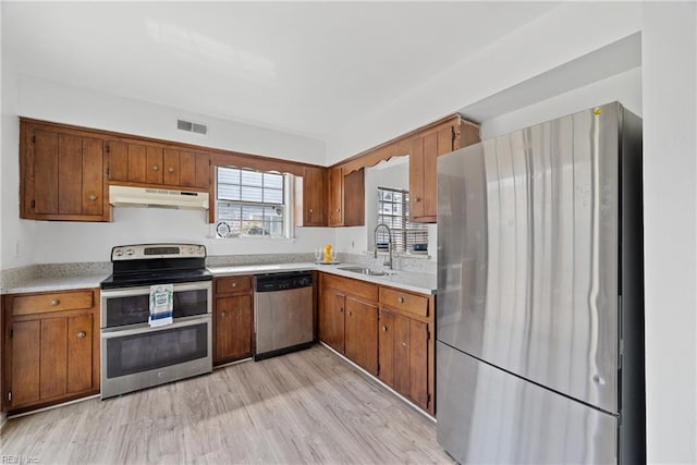 kitchen with under cabinet range hood, light countertops, appliances with stainless steel finishes, visible vents, and a sink