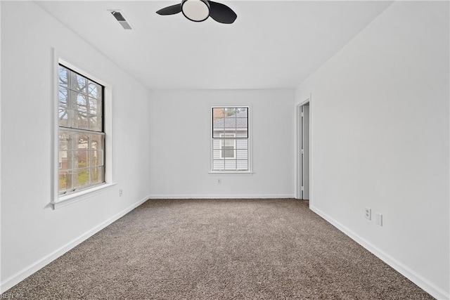 carpeted empty room with baseboards, visible vents, and ceiling fan